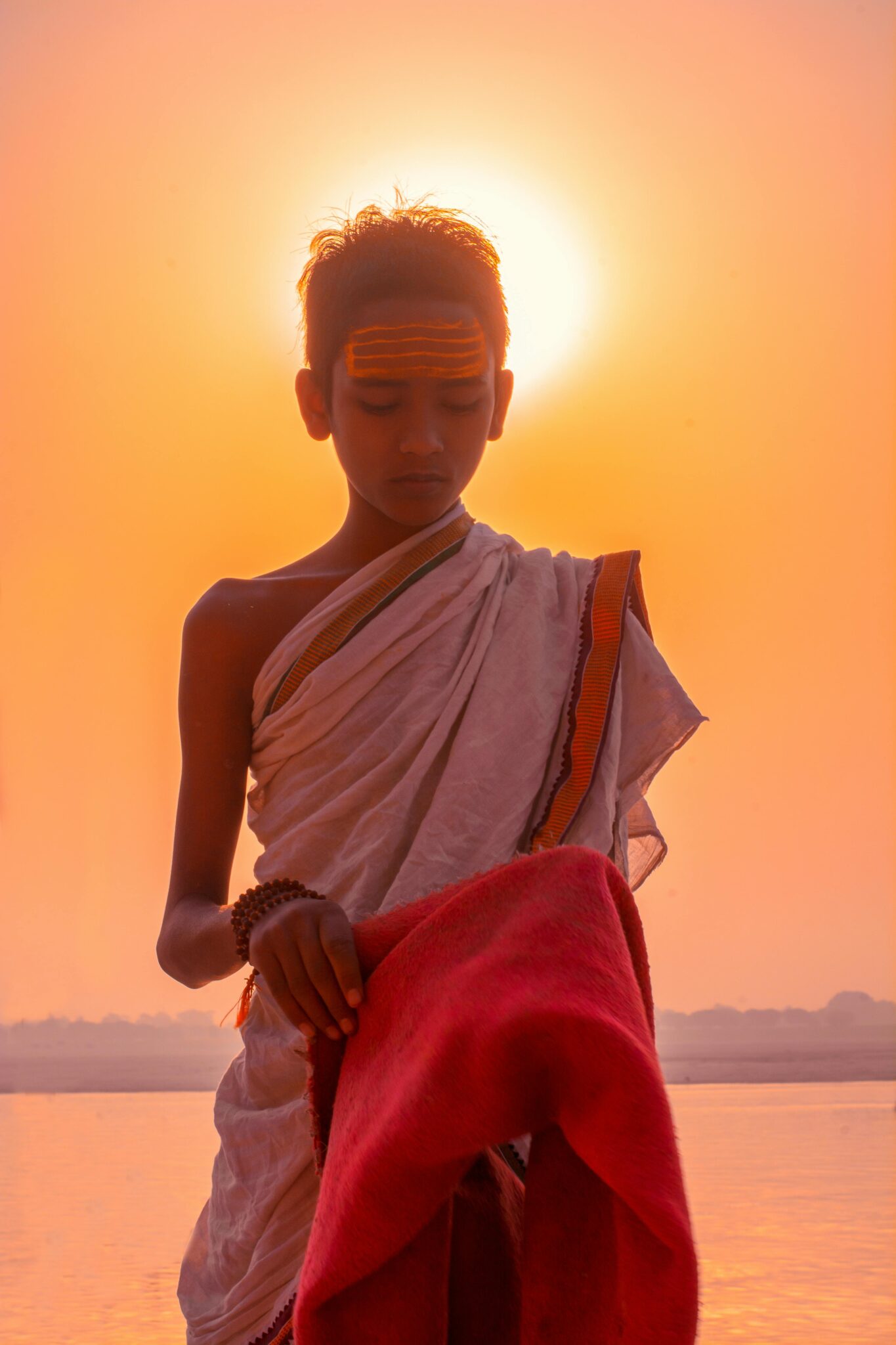 A Brahmin boy with a towel on his head prepares pooja materials for the evening arti ceremony.