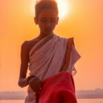 A Brahmin boy with a towel on his head prepares pooja materials for the evening arti ceremony.